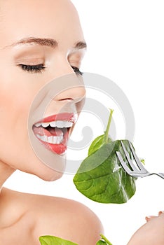 Beautiful caucasian woman eating fresh green luttce from a bowl