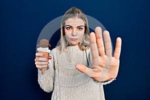 Beautiful caucasian woman eating ice cream with open hand doing stop sign with serious and confident expression, defense gesture