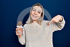 Beautiful caucasian woman eating ice cream pointing finger to one self smiling happy and proud