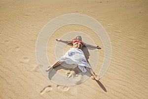 Beautiful caucasian woman enjoying summer holiday vacation travel lay down at the beach on the sand dunes having a sunbath -