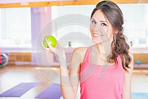 Beautiful caucasian woman after fitness exercise holding green aple