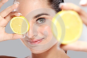 Beautiful caucasian woman holding and showing slices of lemon