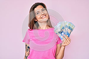 Beautiful caucasian woman holding south african rand banknotes looking positive and happy standing and smiling with a confident