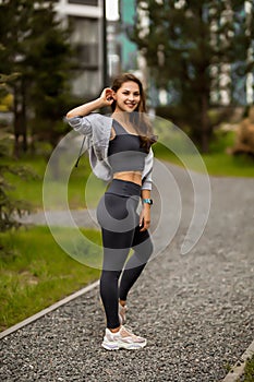 a beautiful caucasian woman with long hair in a tracksuit in the courtyard near the house , lady in grey sportswear on