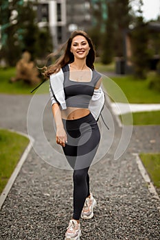 a beautiful caucasian woman with long hair in a tracksuit in the courtyard near the house , lady in grey sportswear on