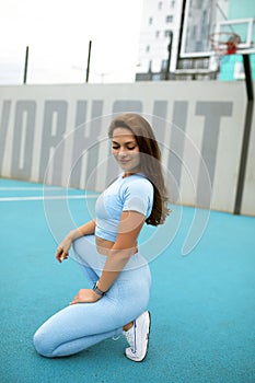 beautiful caucasian woman with long hair in a tracksuit working out, lady in blue sportswear is doing physical training