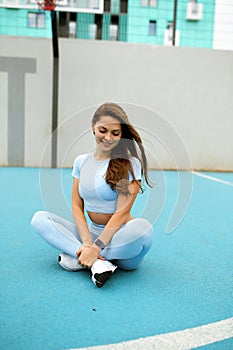 beautiful caucasian woman with long hair in a tracksuit working out, lady in blue sportswear is doing physical training