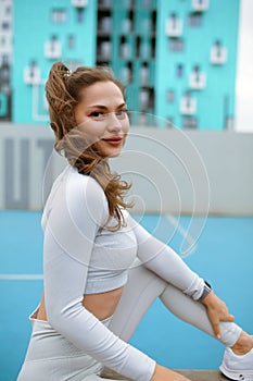 beautiful caucasian woman with long hair in a tracksuit working out, lady in light sportswear is doing physical training