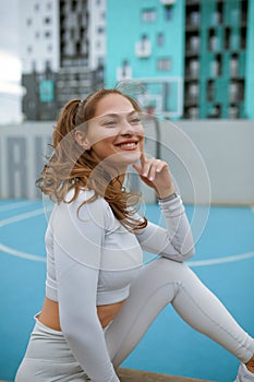beautiful caucasian woman with long hair in a tracksuit working out, lady in light sportswear is doing physical training