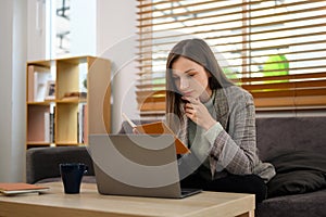 Beautiful caucasian woman looking at laptop screen working remotely at home
