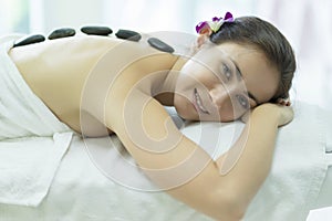 Beautiful caucasian woman relaxation and lying down on massage bed with spa stone