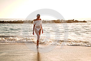 Beautiful caucasian woman on a relaxing walk on empty beach at sunset sea shore