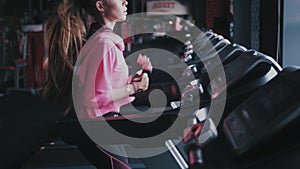 A beautiful Caucasian woman running in a gym on a treadmill.