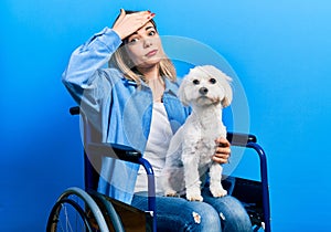 Beautiful caucasian woman sitting on wheelchair hugging dog stressed and frustrated with hand on head, surprised and angry face