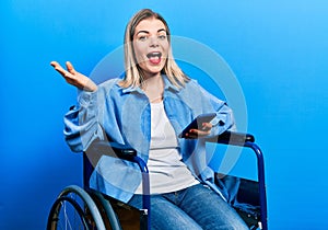 Beautiful caucasian woman sitting on wheelchair using smartphone celebrating achievement with happy smile and winner expression