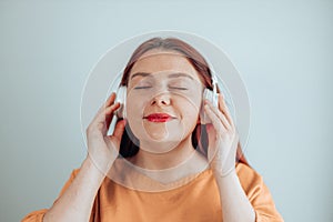 Beautiful Caucasian woman smiling happy and confident wearing headphones listening to music. Girl with closed eyes enjoy