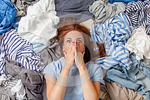 Beautiful caucasian woman smiling and lying down with clutter clothes on the floor.