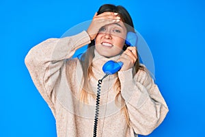 Beautiful caucasian woman speaking on vintage telephone stressed and frustrated with hand on head, surprised and angry face