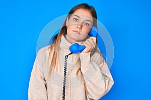 Beautiful caucasian woman speaking on vintage telephone thinking attitude and sober expression looking self confident