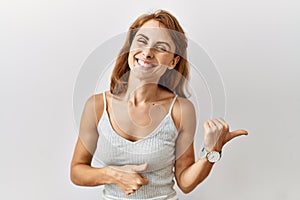 Beautiful caucasian woman standing over isolated background pointing to the back behind with hand and thumbs up, smiling confident