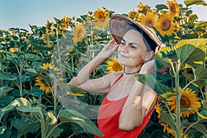 Beautiful Caucasian woman in sunflowers, portrait of a woman wearing a Vietnamese hat walking through a blooming field