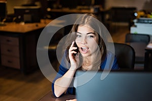 Beautiful caucasian woman talking on a cell phone at a workplace. Portrait of a business woman in the office