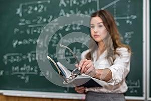 Beautiful caucasian woman teacher standing in classroom near chalkboard