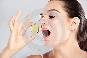 Beautiful caucasian woman trying to eat a slice of lime