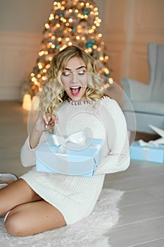 Beautiful caucasian woman is unwrapping the gift box. Celebrating New Year and Christmas, winter holidays.
