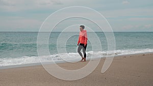 Beautiful caucasian woman is walking along sea beach, enjoying scenery and nature. Freedom and happiness. Female walks on beach al