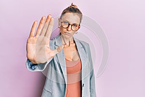 Beautiful caucasian woman wearing business jacket and glasses doing stop sing with palm of the hand