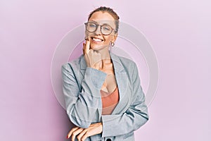 Beautiful caucasian woman wearing business jacket and glasses looking confident at the camera with smile with crossed arms and