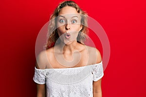 Beautiful caucasian woman wearing casual clothes over red background scared and amazed with open mouth for surprise, disbelief