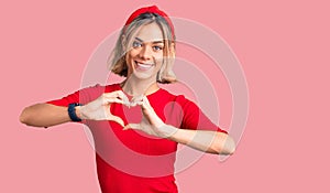 Beautiful caucasian woman wearing casual clothes and red diadem smiling in love showing heart symbol and shape with hands
