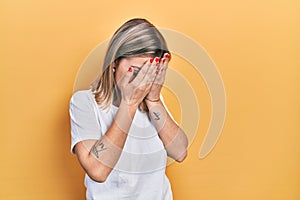 Beautiful caucasian woman wearing casual white t shirt with sad expression covering face with hands while crying