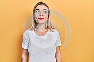 Beautiful caucasian woman wearing casual white t shirt smiling looking to the side and staring away thinking