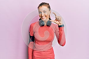 Beautiful caucasian woman wearing sportswear and arm band smiling and confident gesturing with hand doing small size sign with