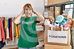 Beautiful caucasian woman wearing volunteer t shirt at donations stand crazy and scared with hands on head, afraid and surprised