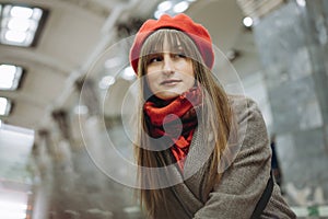 Beautiful Caucasian woman wearing warm coat, beret and scarf sitting alone on Saint Petersburg metro station