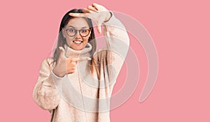 Beautiful caucasian woman wearing wool winter sweater smiling making frame with hands and fingers with happy face