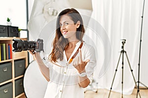 Beautiful caucasian woman working as photographer at photography studio beckoning come here gesture with hand inviting welcoming