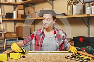 Beautiful caucasian young brown-hair woman working in carpentry workshop at table place.