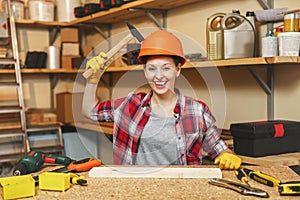 Beautiful caucasian young brown-hair woman working in carpentry workshop at table place.