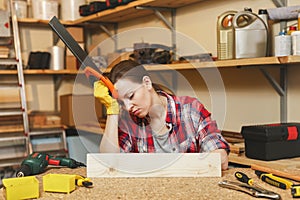 Beautiful caucasian young brown-hair woman working in carpentry workshop at table place.