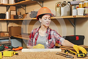 Beautiful caucasian young brown-hair woman working in carpentry workshop at table place.