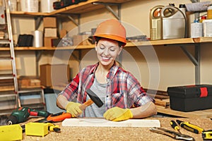 Beautiful caucasian young brown-hair woman working in carpentry workshop at table place.