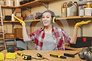 Beautiful caucasian young brown-hair woman working in carpentry workshop at table place.