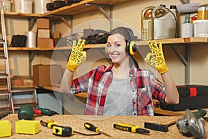 Beautiful caucasian young brown-hair woman working in carpentry workshop at table place.