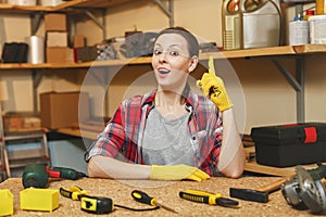 Beautiful caucasian young brown-hair woman working in carpentry workshop at table place.