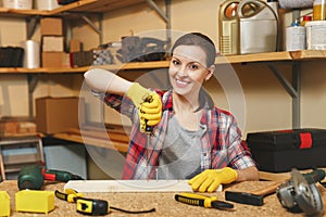 Beautiful caucasian young brown-hair woman working in carpentry workshop at table place.